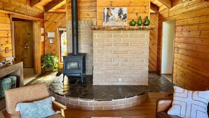 Een knus interieur van een lodge met een stenen openhaard, houten wanden en een rustiek houten plafond.