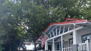 Une maison avec un porche, un drapeau américain et une clôture en bois peinte en blanc.