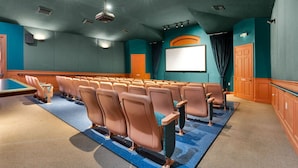 A movie theater with rows of seats, a large screen, and a projector. - Resort-Style Villa | Pool, Spa & Game Room! (Kissimmee)