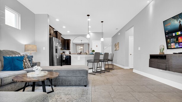 A modern living room with a grey sofa, a coffee table, and a dining area with bar stools. - 5Br Davenport Home W/ Pool & Private Hot Tub (Davenport)