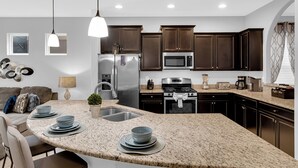A modern kitchen with granite countertops, stainless steel appliances, and dark wooden cabinets. - 5Br Davenport Home W/ Pool & Private Hot Tub (Davenport)