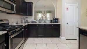 Une cuisine moderne avec des meubles de couleur sombre, des appareils en acier inoxydable et une porte blanche.