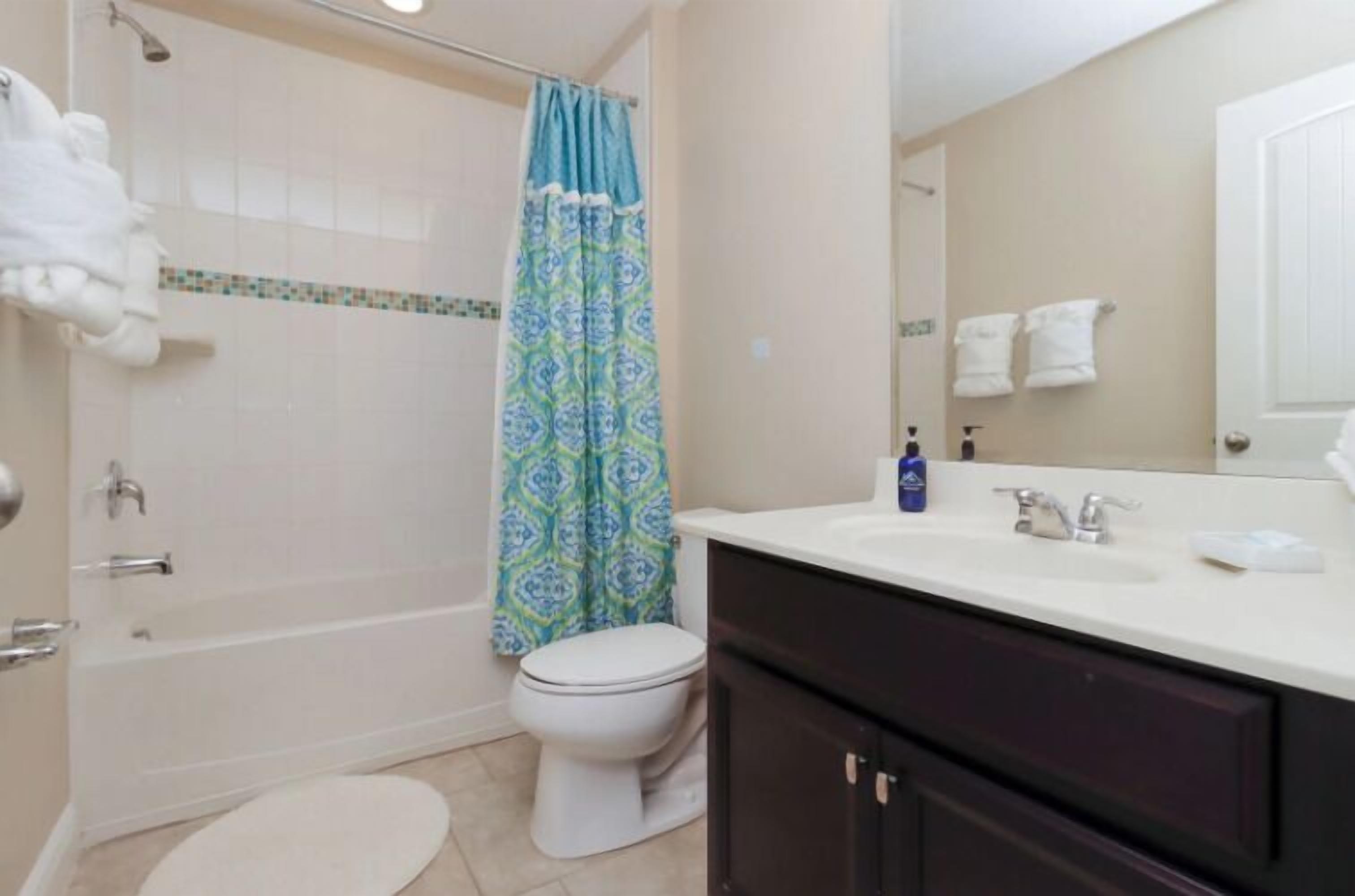 A bathroom with a shower, toilet, and sink.