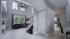 A spacious living area with a staircase, a large window, and a modern ceiling light fixture. - 6Br Retreat W/ South Pool, Spa & Game Room Fun (Kissimmee)