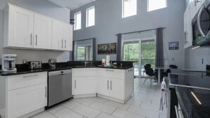 A modern kitchen with white cabinets, a black countertop, and a large window providing natural light. - 6Br Retreat W/ South Pool, Spa & Game Room Fun (Kissimmee)