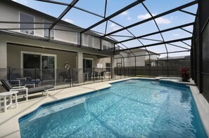 En indendørs swimmingpool med glasloft, liggestole og udsigt til himlen.