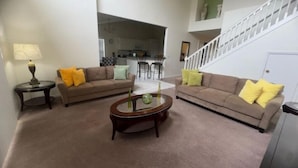 A living room with two sofas, a coffee table, and a lamp. A staircase is visible in the background. - South Facing W/ Private Pool & Spa (Kissimmee)