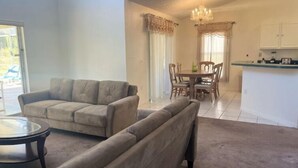A living room with a sofa, a coffee table, and a dining area with a table and chairs. - South Facing W/ Private Pool & Spa (Kissimmee)