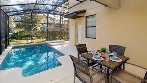 Un espacio al aire libre cubierto con piscina, mesa y sillas.