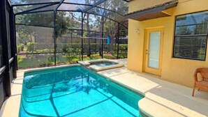 Una piscina con cerramiento de vidrio, una puerta y una silla.
