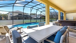 A covered outdoor area with a pool, seating, and a bar. - Relax & Unwind – Stunning Home W/ Private Pool! (Kissimmee)