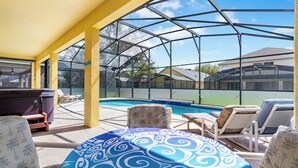 A covered outdoor area with a pool, lounge chairs, and a table with a patterned tablecloth. - Relax & Unwind – Stunning Home W/ Private Pool! (Kissimmee)