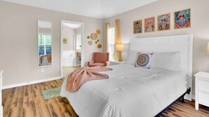 Une chambre à coucher avec un grand lit, une chaise, une table de chevet et un miroir.