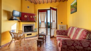 Una sala de estar con chimenea, un sofá, un televisor y una zona de comedor.