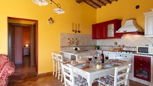 Una cocina con comedor, que presenta una decoración en tonos rojo y blanco, un salpicadero de azulejos y diversos electrodomésticos.