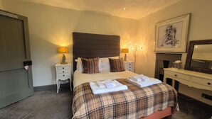 A hotel room with a bed, bedside tables, a dresser, a mirror, and a painting on the wall. - Gate Lodge - historic rural cottage with hot tub, Aberdeenshire (Fettercairn)