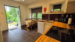 A kitchen with a dining table, a dishwasher, a microwave, and a sink. - Gate Lodge - historic rural cottage with hot tub, Aberdeenshire (Fettercairn)