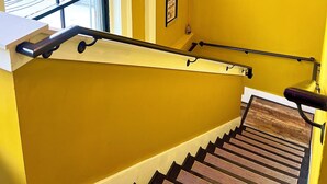 A staircase with a handrail, a window with a view of the street, and a wall with circular wooden panels. - Off to the Races Retreat - Hidden Clues Inside (Frankfort)