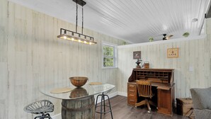 A dining area with a wooden table, stools, and a vintage-style desk. - Beyond Charming Luxury Barndominium - Get away without going far away! (Howey-in-the-Hills)