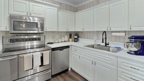 A modern kitchen with white cabinetry, stainless steel appliances, and a blue stand mixer. - Beyond Charming Luxury Barndominium - Get away without going far away! (Howey-in-the-Hills)