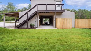 A two-story building with a covered outdoor area and a staircase leading to the upper floor. - Beyond Charming Luxury Barndominium - Get away without going far away! (Howey-in-the-Hills)