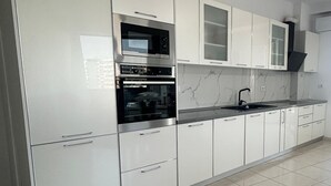 Una cocina moderna con armarios blancos, electrodomésticos de acero inoxidable y piso de baldosas.