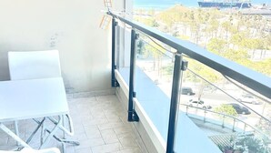 Un balcón con vista a un barco y montañas a lo lejos.