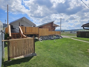 A two-story wooden cabin with a covered porch and a stone foundation.