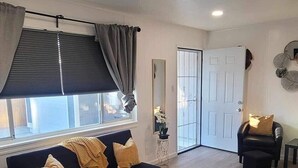 A modern living room with a black sofa, a coffee table, and a patterned rug. - The Hideaway (Sacramento)