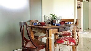 Una mesa de comedor preparada con sillas, una planta y diferentes vasos.