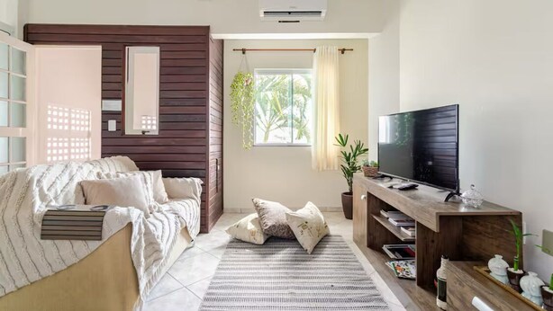 Una sala de estar moderna con un sofá, un televisor y un mueble de televisión de madera.