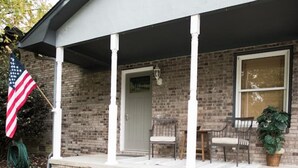 Een huis met twee verdiepingen, een gevel van baksteen, een veranda met witte zuilen en een vlag.
