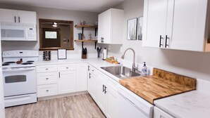 Een moderne keuken met witte kasten, een houten aanrecht, een roestvrijstalen spoelbak en een magnetron.
