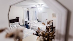 Une chambre avec deux lits, un ventilateur de plafond et une table de chevet avec une lampe.