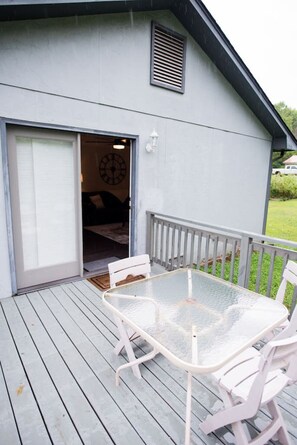 A patio with a glass table and white chairs, a door leading to a room, and a small white fence. - Country home, 11 mi to UTK (Powell)