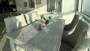 Een moderne eethoek met een rechthoekige tafel en grijze fauteuils.