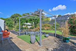 A patio area with a pergola, seating, and potted plants.