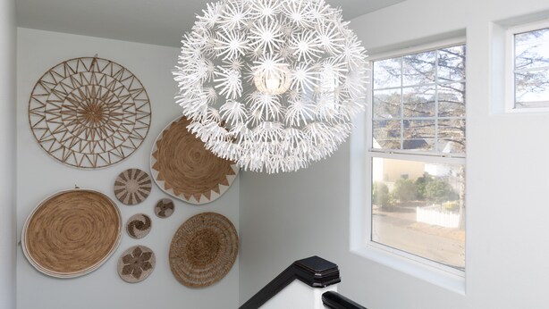 A room with a white ceiling, a large window, and various wall decorations including woven baskets and geometric patterns. - OMalley's Ocean Getaway—Nelscott Bch-Dog OK-EV (Lincoln City)