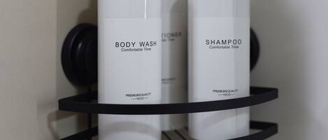 A black metal shelf with three white bottles labeled 'BODY WASH' and 'SHAMPOO' on a wall.