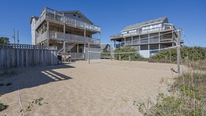 Een tweelaags gebouw aan het strand met een balkon en een zandvlakte.