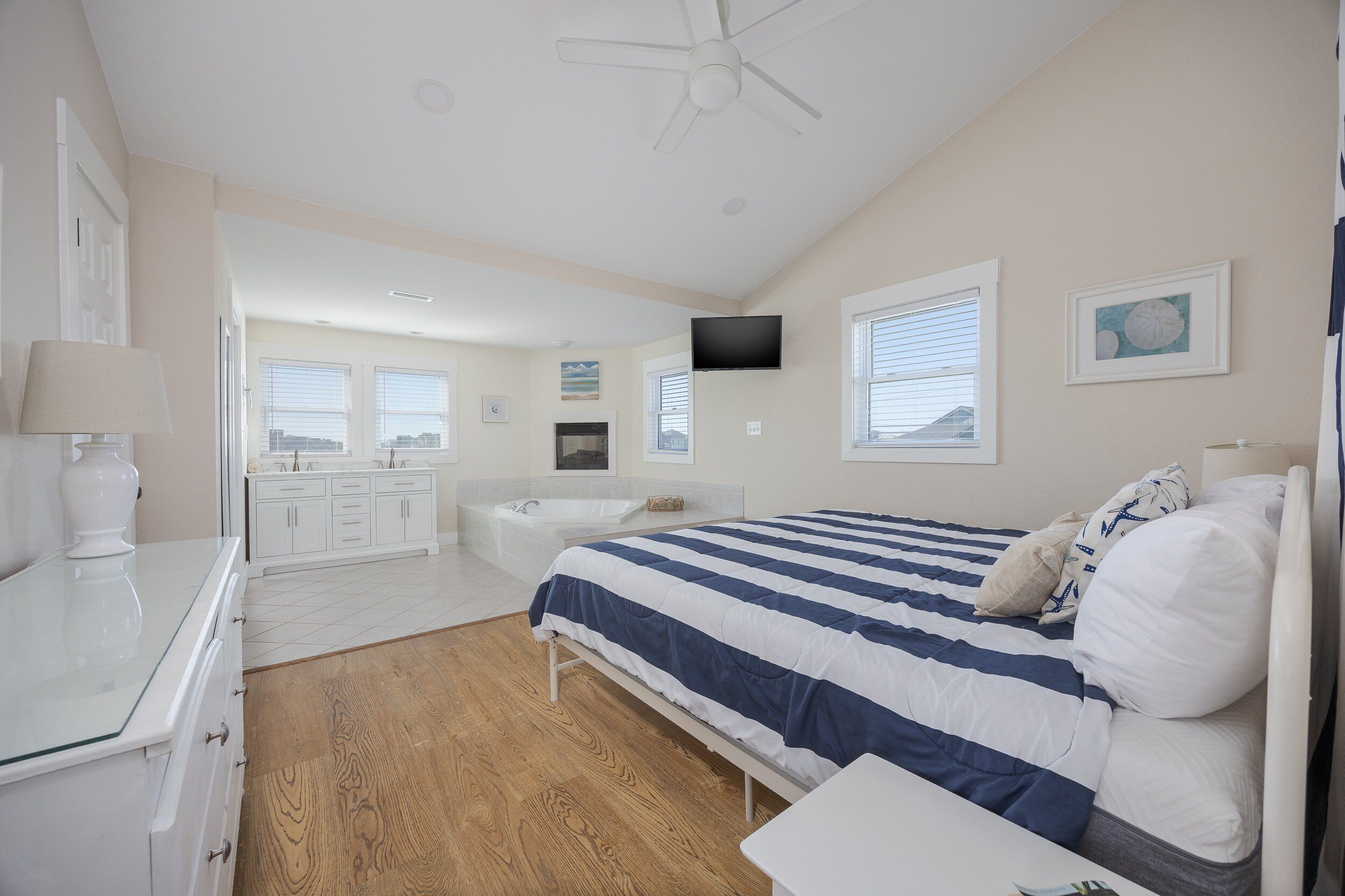 A bedroom with a bed, a TV, a desk, and a bathroom in the background.