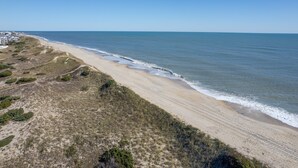 Een kustlandschap met een zandstrand en helder uitzicht op de oceaan.