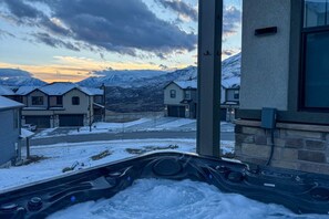 A hot tub with a snowy landscape and mountains in the background.