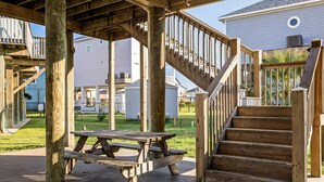 Una terraza de madera con una mesa de picnic y una escalera que lleva a otra terraza.