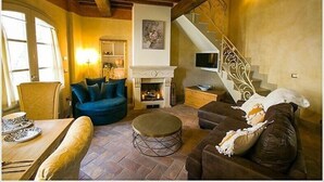Een gezellige woonkamer met een open haard, een blauwe bank, een bruine bank en een ronde salontafel.