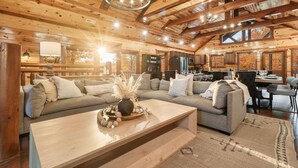 A spacious log cabin interior with a large living area, a dining area, and a kitchen.