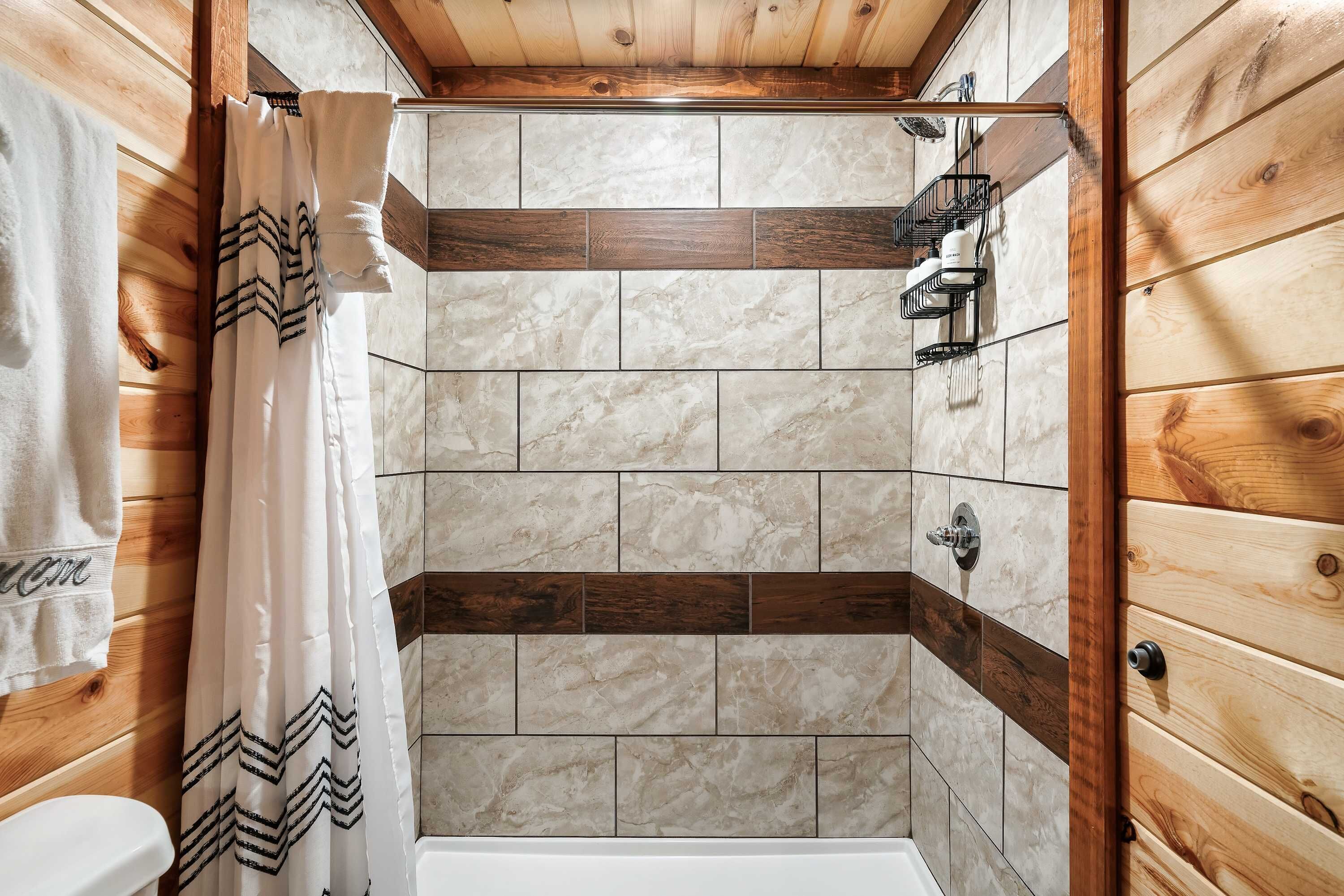 A shower area with a wooden ceiling, tiled walls, and a shower curtain.