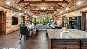 A spacious wooden cabin with a large dining area, granite countertops, and a kitchen with modern appliances.