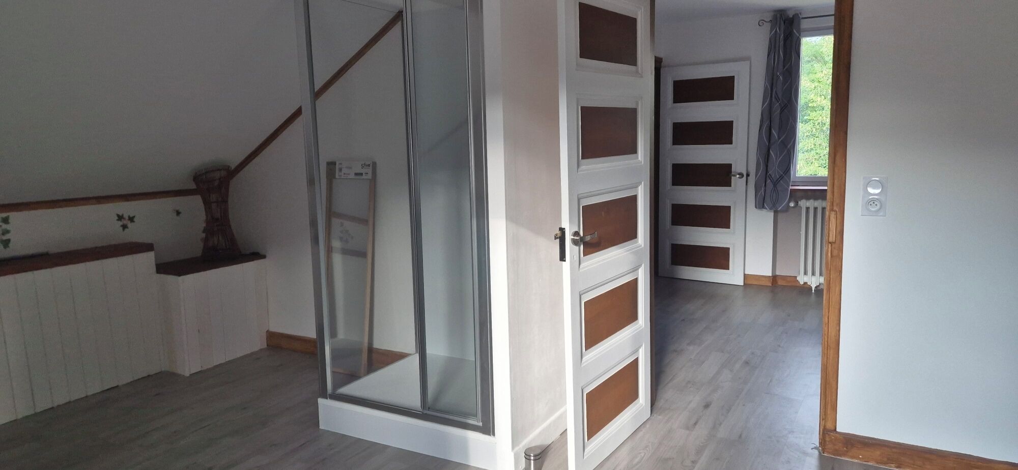 A hallway with a glass door, a staircase, and a door with multiple panels.