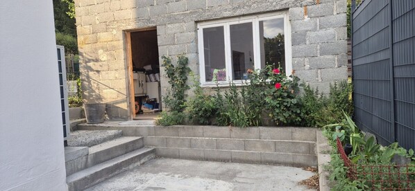 A stone building with a small front yard, a wooden door, and a window with a view of the sky. - Gîte Sancy ***, comfort and relaxation in Auvergne (Saint-Nectaire)
